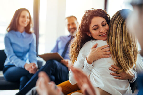 Support group patients hug each other during the addiction therapy session