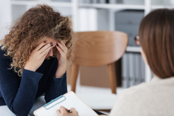 Sad woman hiding her face during meeting with personal therapist for CBT 