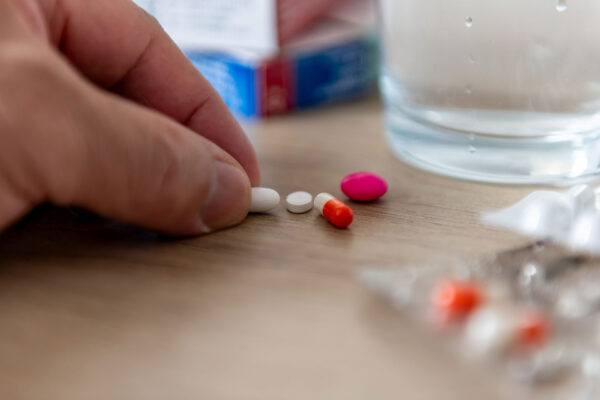 A person taking prescription medicine picking up a tablet on a worktop