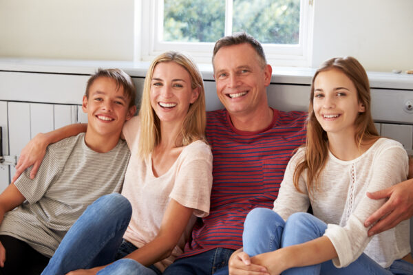 Smiling family of four outdoors, showing how to help a loved one with addiction through steady support