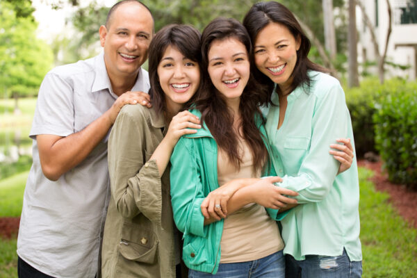 Family of four embracing in a green park after learning how to help a loved one with addiction